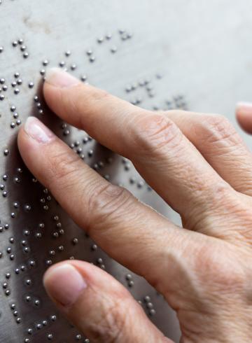 Hand reading braille.