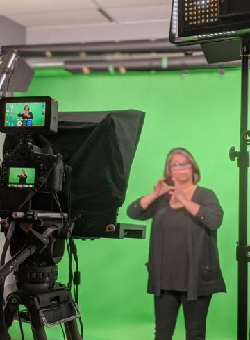 Sign language interpreter in front of a camera.