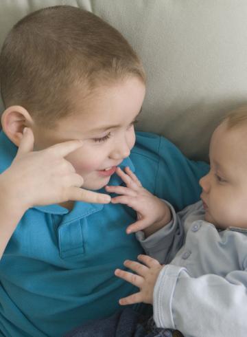 Boy signing the phrase 'I Love You ' in American sign language while communicating with his brother
