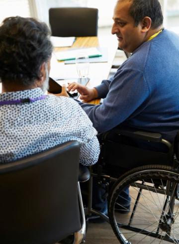 Businessman in wheelchair talking with colleague in meeting
