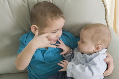 Boy signing the phrase 'I Love You ' in American sign language while communicating with his brother