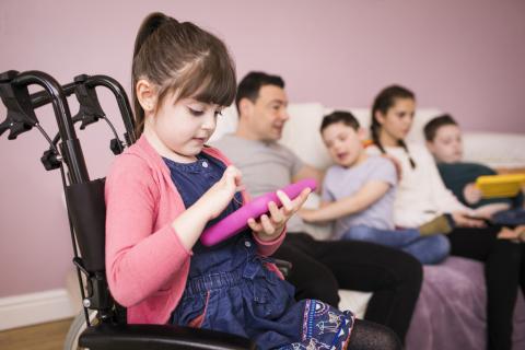 Girl with Down Syndrome in wheelchair using digital tablet